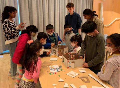 Children gather around a table to build cardboard houses