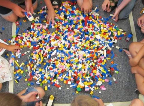 Children gather around a pile of Lego.