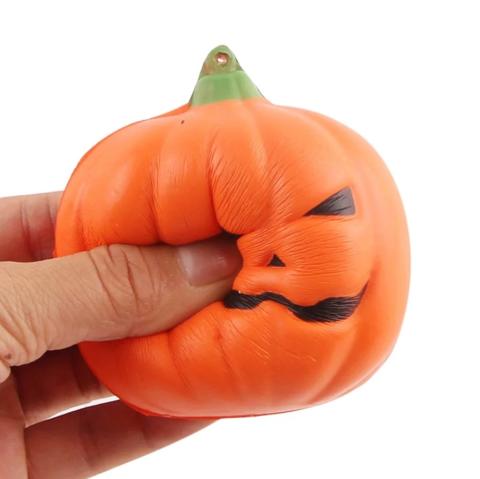 A hand squeezes a foam jack-o-lantern.