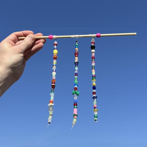 Strings of beads held up against a blue sky.