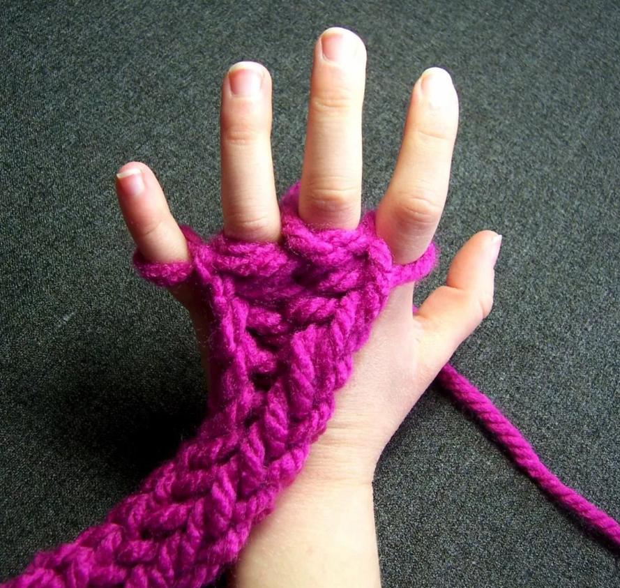 Purple yarn knitted around a child's fingers.